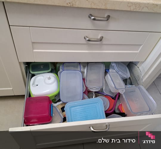 מגירת ארון מטבח עמוסה בקופסאות אחסון מפלסטיק בצבעים שונים